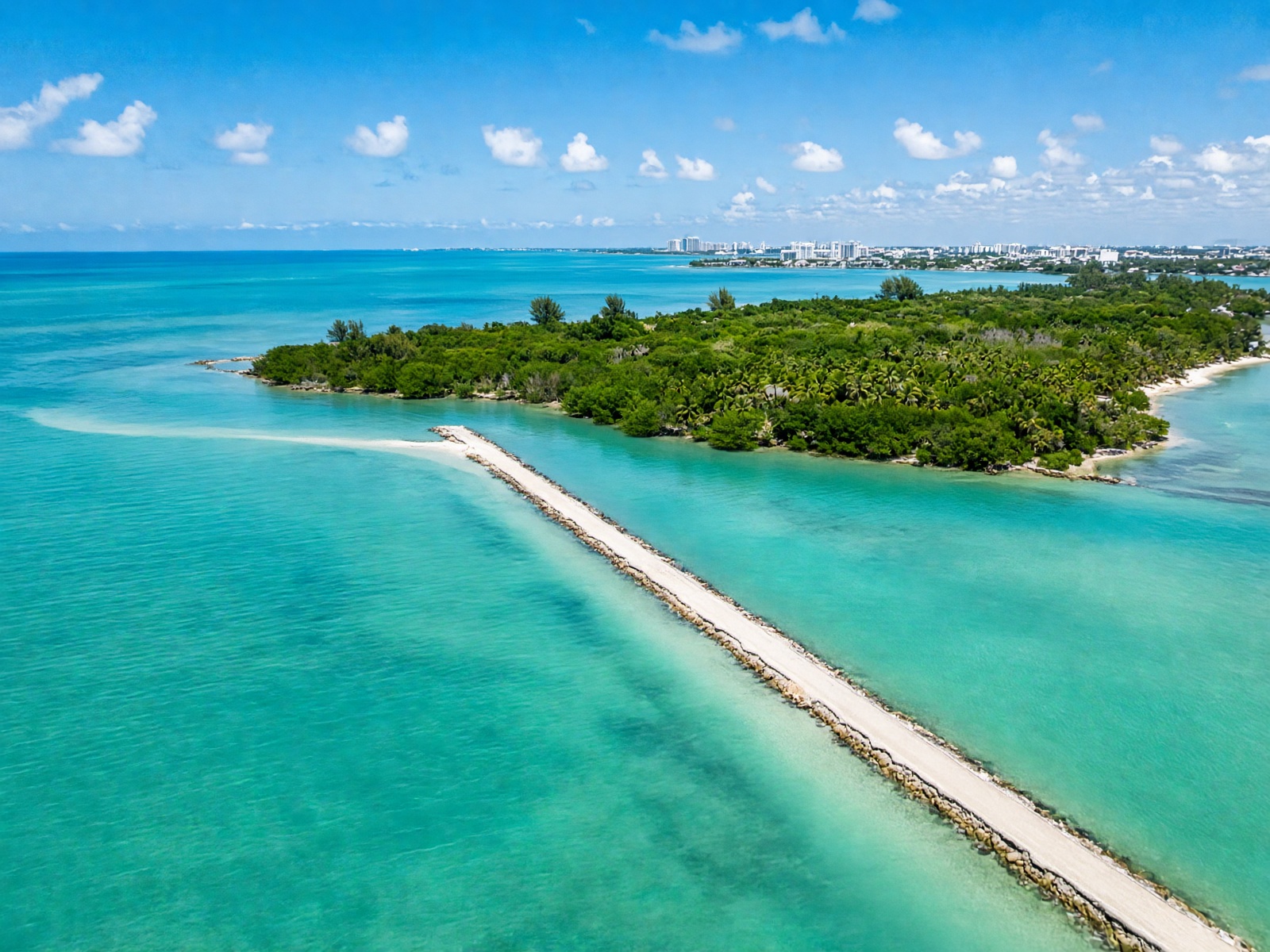 A causeway over turquoise water toward a tropical island